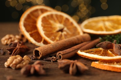 Photo of Different spices and dried orange slices on wooden table, closeup. Christmas season