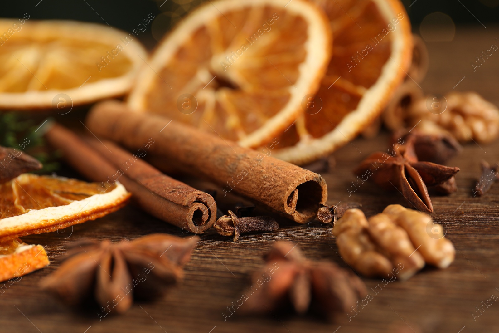 Photo of Different spices and dried orange slices on wooden table, closeup. Christmas season