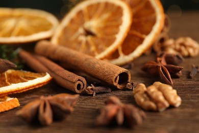 Photo of Different spices and dried orange slices on wooden table, closeup. Christmas season