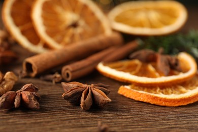 Photo of Different spices and dried orange slices on wooden table, closeup. Christmas season