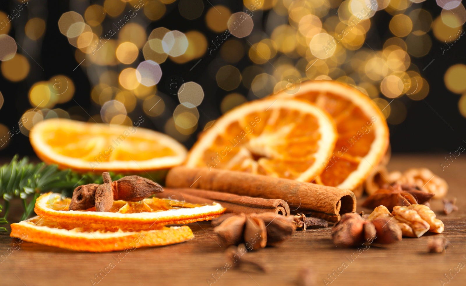 Photo of Different spices, dried orange slices and fir tree branches on wooden table, closeup. Christmas season