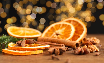 Photo of Different spices, dried orange slices and fir tree branches on wooden table, closeup. Christmas season