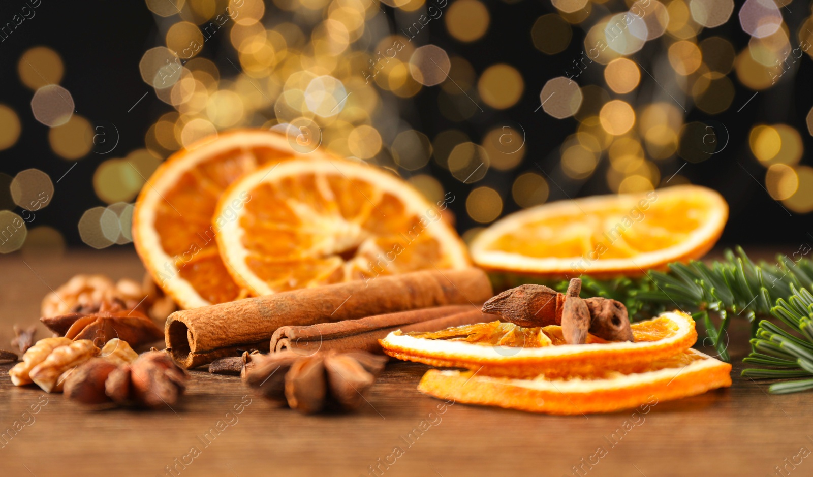 Photo of Different spices, dried orange slices and fir tree branches on wooden table, closeup. Christmas season