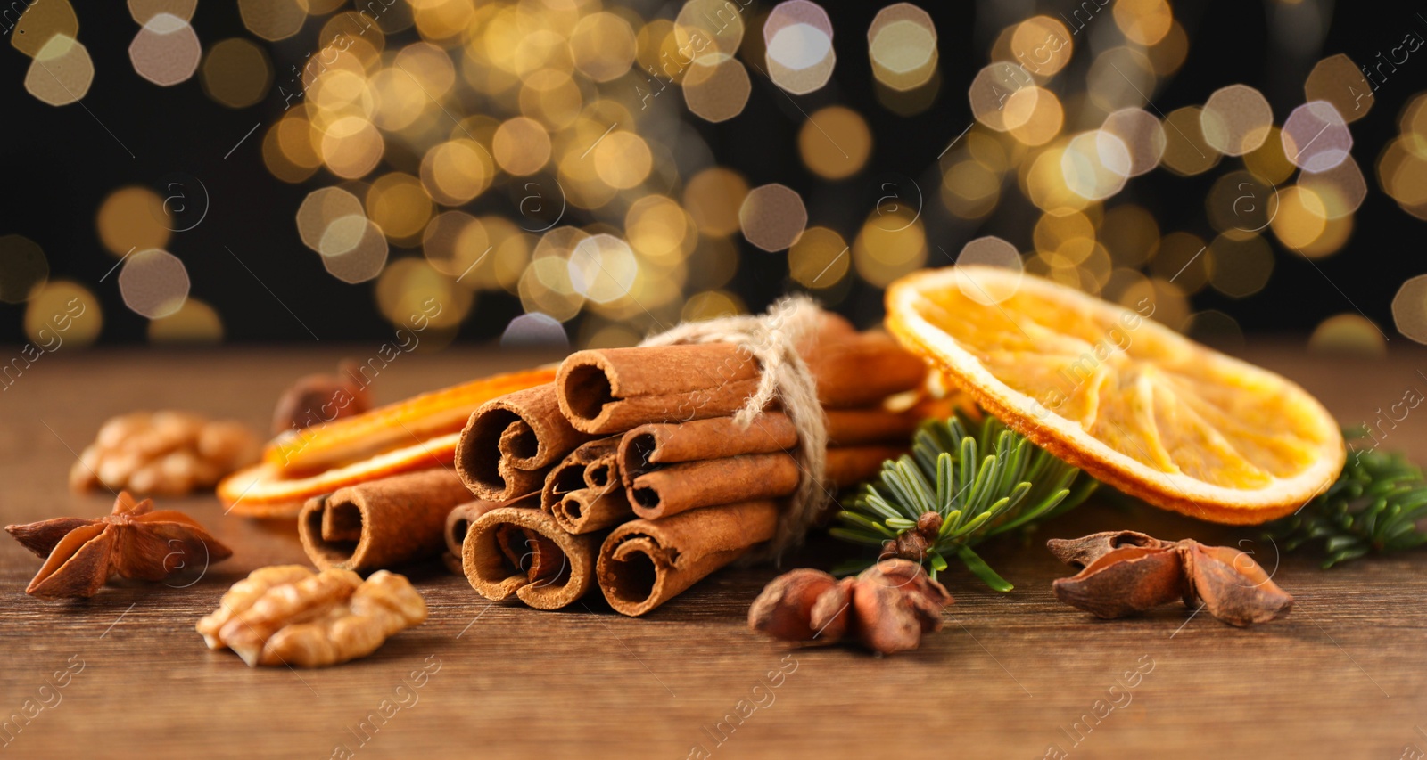 Photo of Different spices, dried orange slices and fir tree branches on wooden table, closeup. Christmas season