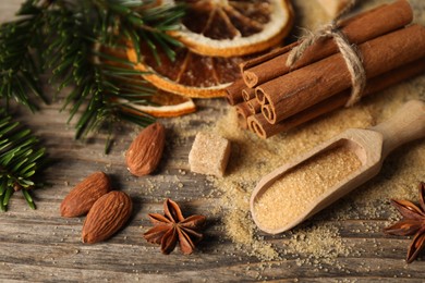 Photo of Different spices, dried orange slices and fir tree branches on wooden table, closeup. Christmas season