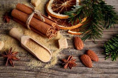 Photo of Different spices, dried orange slices and fir tree branches on wooden table, closeup. Christmas season