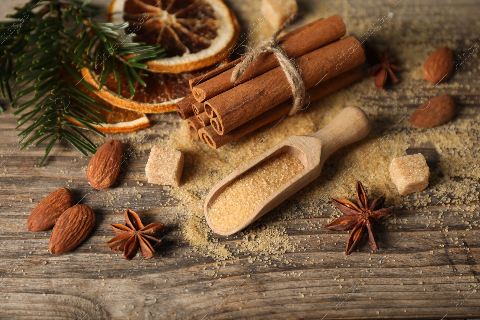 Photo of Different spices, dried orange slices and fir tree branches on wooden table, closeup. Christmas season