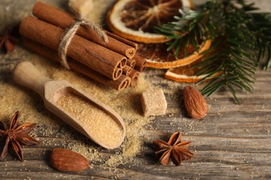 Photo of Different spices, dried orange slices and fir tree branches on wooden table, closeup. Christmas season