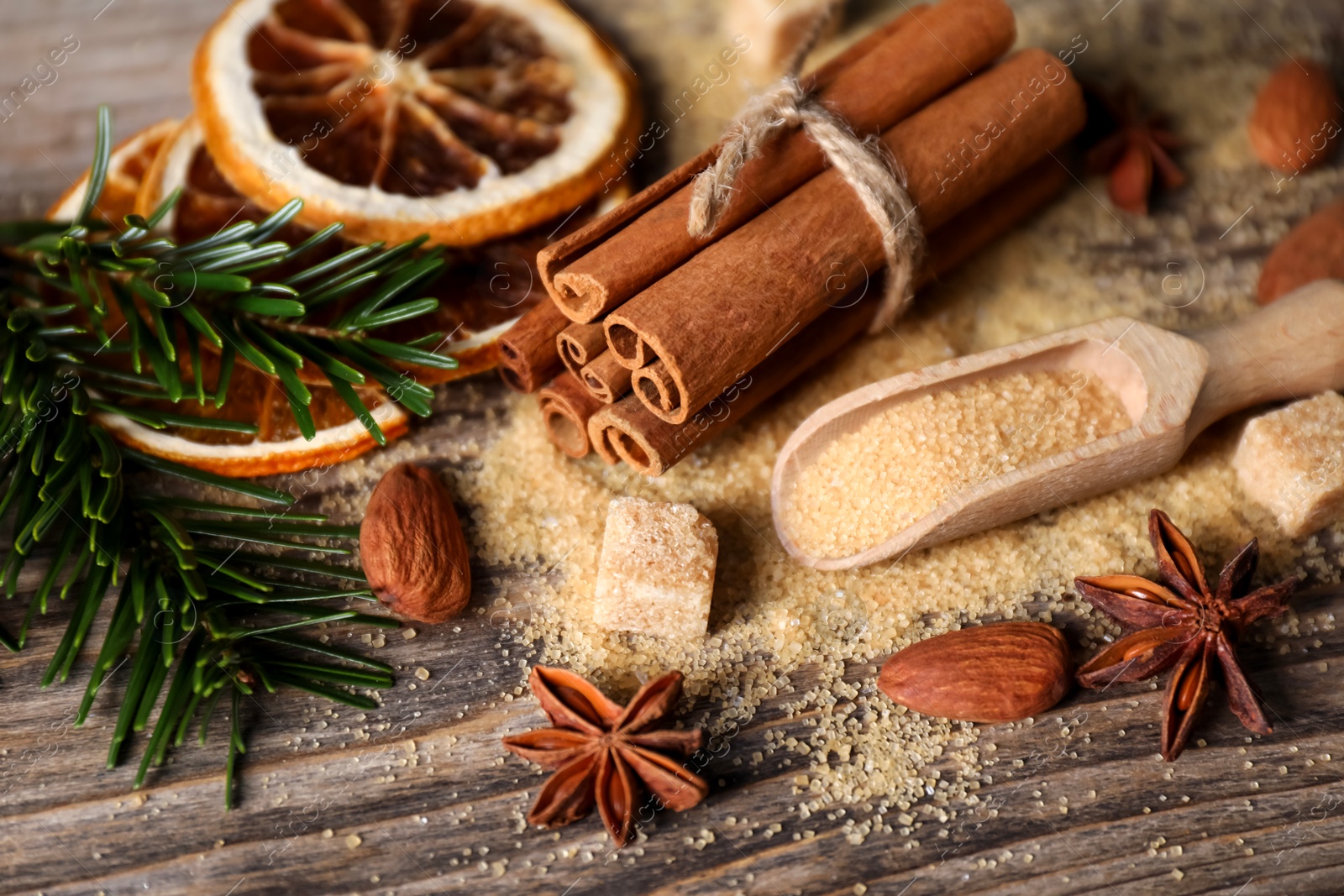 Photo of Different spices, dried orange slices and fir tree branches on wooden table, closeup. Christmas season