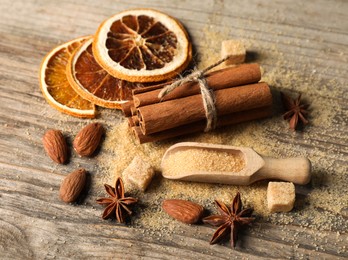 Photo of Different spices and dried orange slices on wooden table, above view. Christmas season