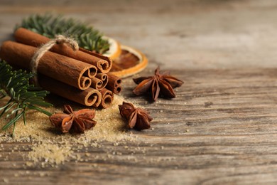 Photo of Different spices, dried orange slices and fir tree branches on wooden table, closeup with space for text. Christmas season