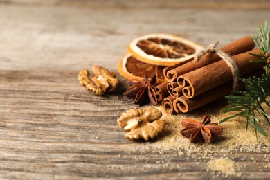 Photo of Different spices, dried orange slices and fir tree branches on wooden table, closeup with space for text. Christmas season