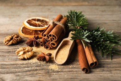 Photo of Different spices, dried orange slices and fir tree branches on wooden table, closeup. Christmas season