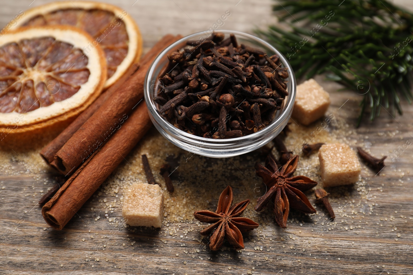 Photo of Different spices, dried orange slices and fir tree branches on wooden table, closeup. Christmas season