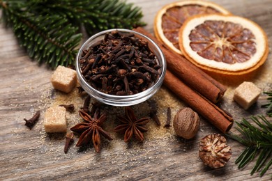 Different spices, dried orange slices and fir tree branches on wooden table, closeup. Christmas season