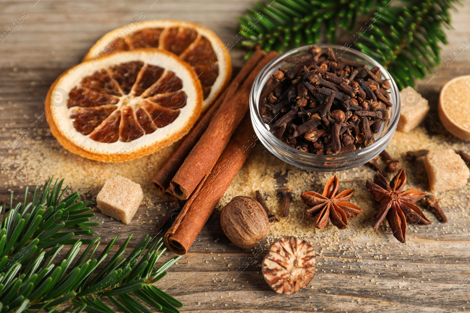 Photo of Different spices, dried orange slices and fir tree branches on wooden table, closeup. Christmas season