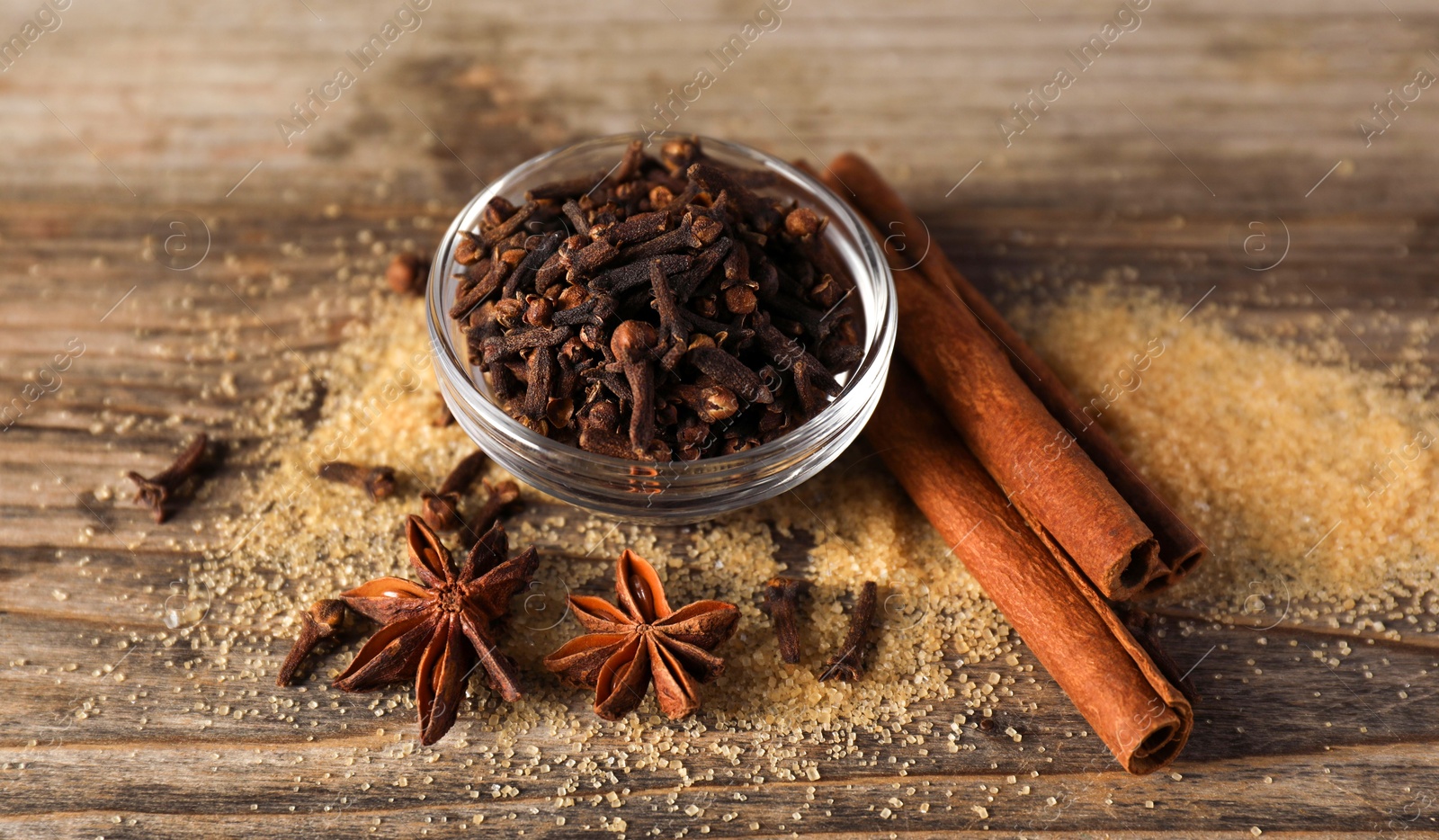 Photo of Different spices and dried orange slices on wooden table, closeup. Christmas season