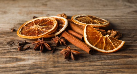 Photo of Different spices and dried orange slices on wooden table, closeup. Christmas season