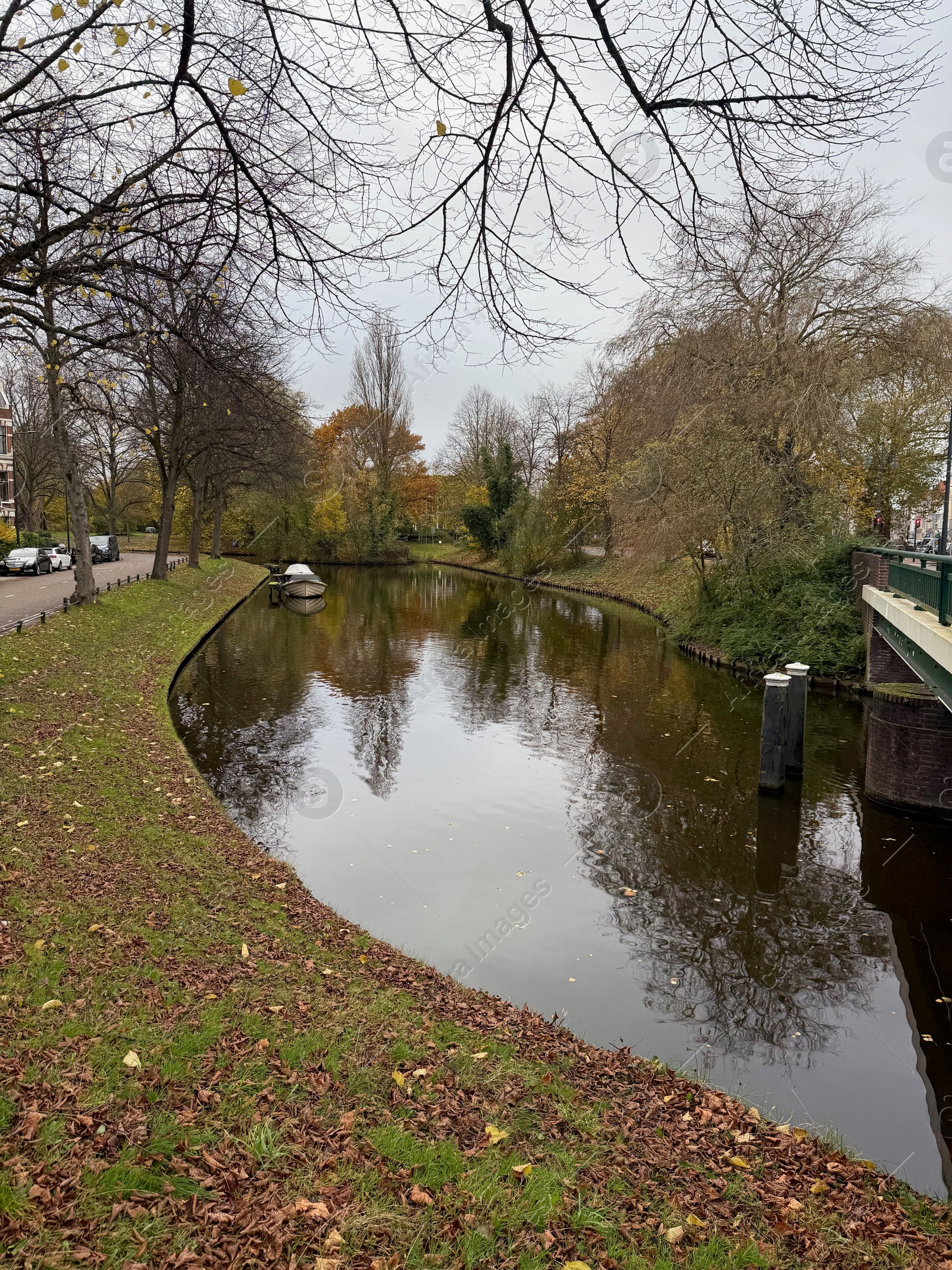 Photo of Beautiful view of canal with moored boat and colorful fallen leaves on autumn day