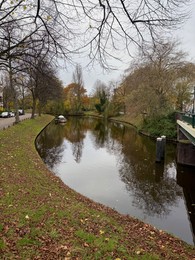 Photo of Beautiful view of canal with moored boat and colorful fallen leaves on autumn day