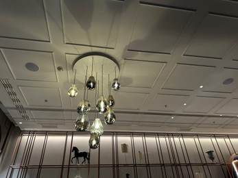 Berlin, Germany - November 05, 2024: Stylish chandelier on ceiling in hotel Luc, Autograph Collection, low angle view