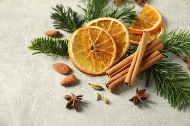 Photo of Different spices, dried orange slices and fir tree branches on light grey table, closeup. Christmas season