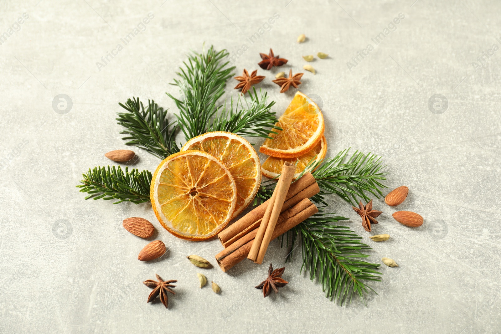 Photo of Different spices, dried orange slices and fir tree branches on light grey table, above view. Christmas season