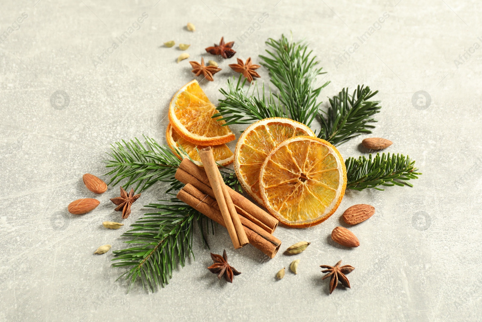 Photo of Different spices, dried orange slices and fir tree branches on light grey table, above view. Christmas season