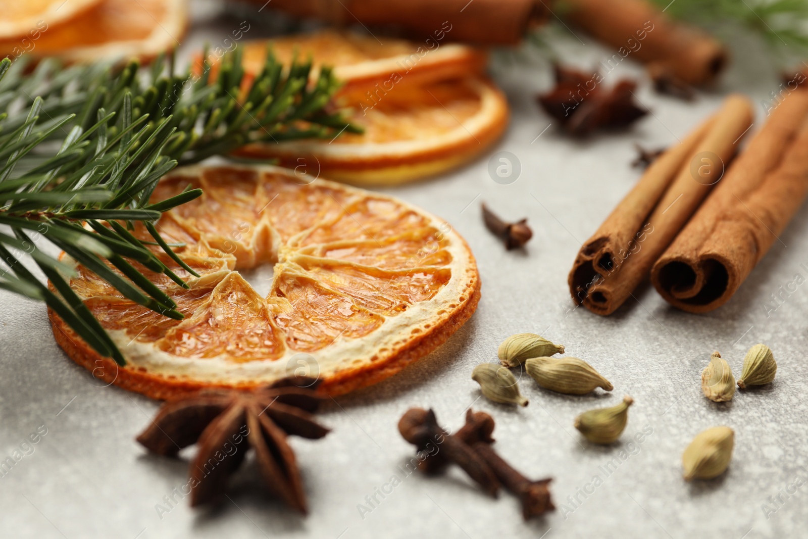 Photo of Different spices, dried orange slices and fir tree branches on light grey table, closeup. Christmas season