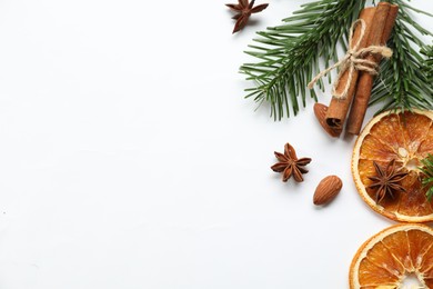 Photo of Different spices, dried orange slices and fir tree branches on white table, flat lay with space for text. Christmas season