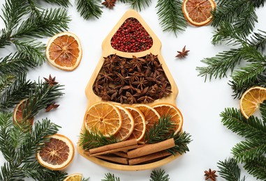 Photo of Different spices, dried orange slices and fir tree branches on white table, flat lay. Christmas season