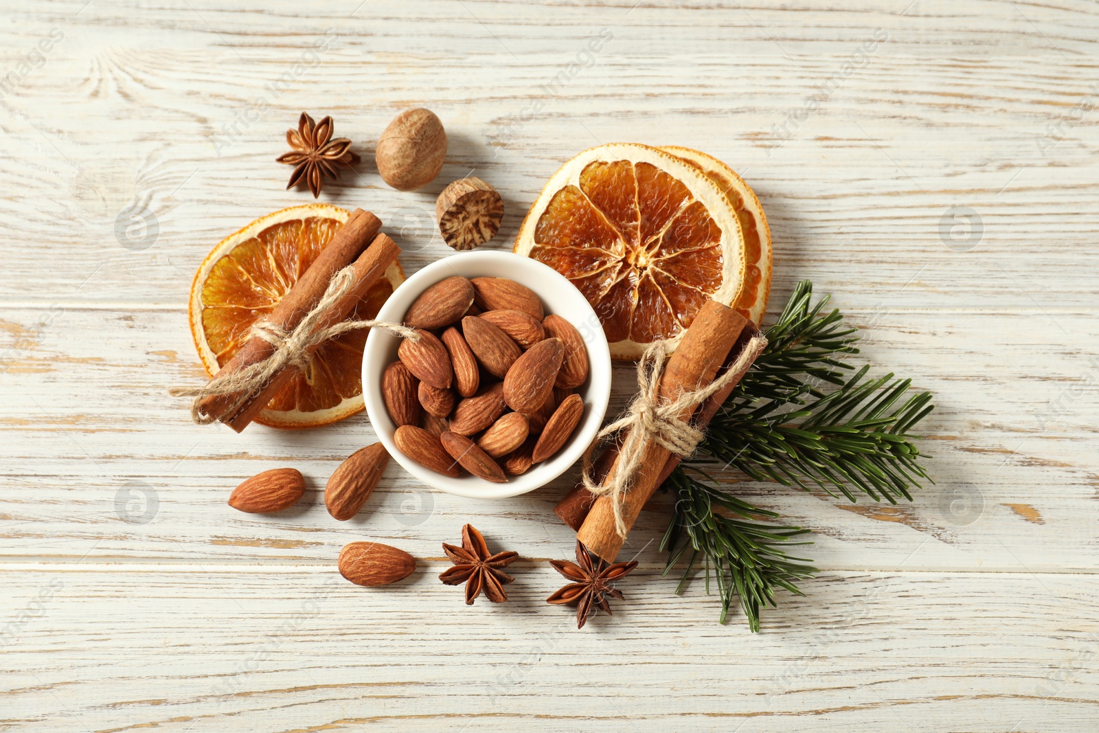 Photo of Different spices, dried orange slices and fir tree branches on white wooden table, flat lay. Christmas season