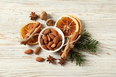 Photo of Different spices, dried orange slices and fir tree branches on white wooden table, flat lay. Christmas season