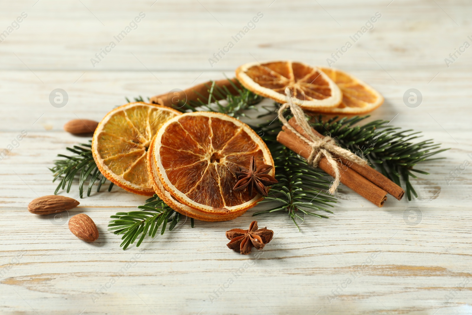 Photo of Different spices, dried orange slices and fir tree branches on white wooden table. Christmas season