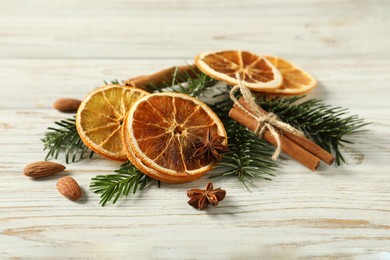 Photo of Different spices, dried orange slices and fir tree branches on white wooden table. Christmas season