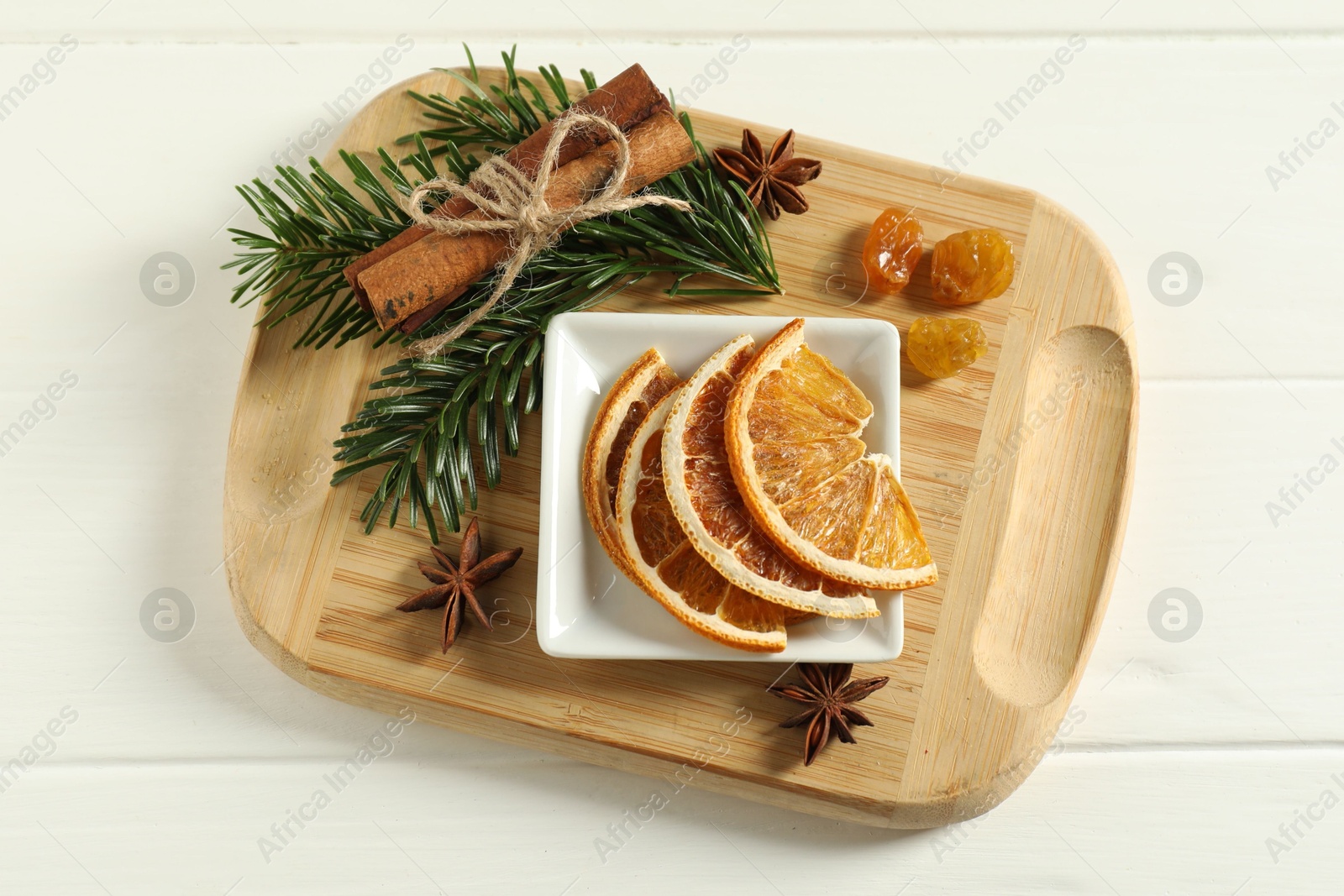 Photo of Different spices, dried orange slices and fir tree branches on white wooden table, flat lay. Christmas season