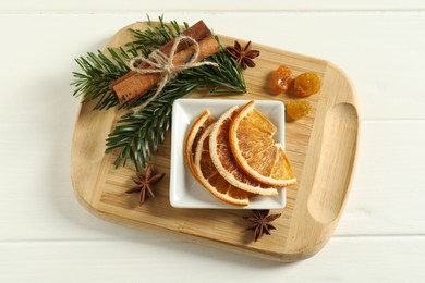 Photo of Different spices, dried orange slices and fir tree branches on white wooden table, flat lay. Christmas season