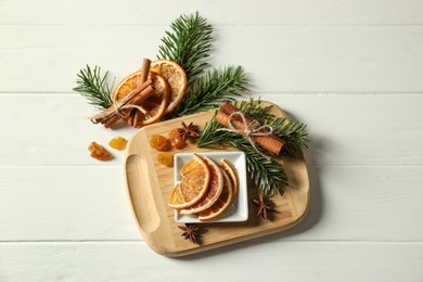 Photo of Different spices, dried orange slices and fir tree branches on white wooden table, flat lay. Christmas season