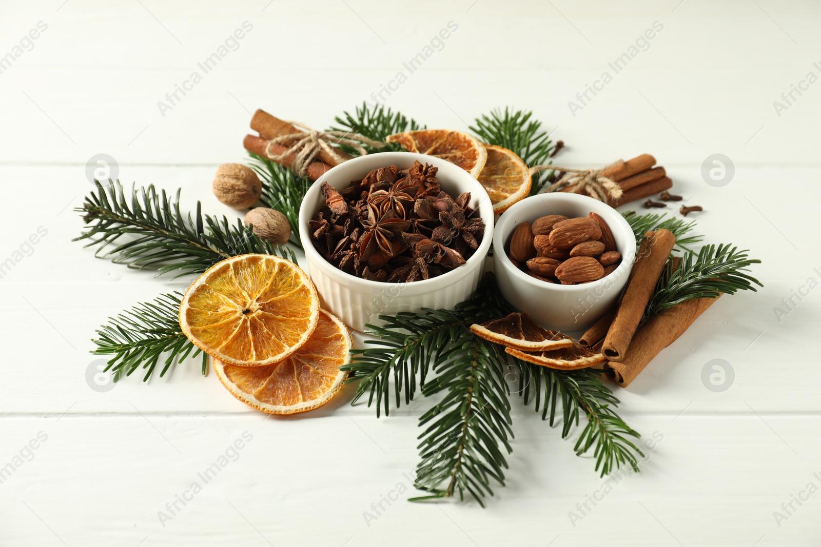 Photo of Different spices, dried orange slices and fir tree branches on white wooden table. Christmas season