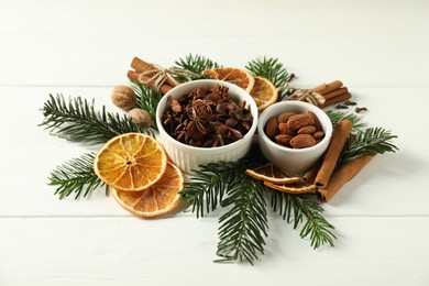 Photo of Different spices, dried orange slices and fir tree branches on white wooden table. Christmas season