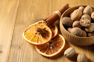 Photo of Different spices and dried orange slices on wooden table, closeup with space for text. Christmas season