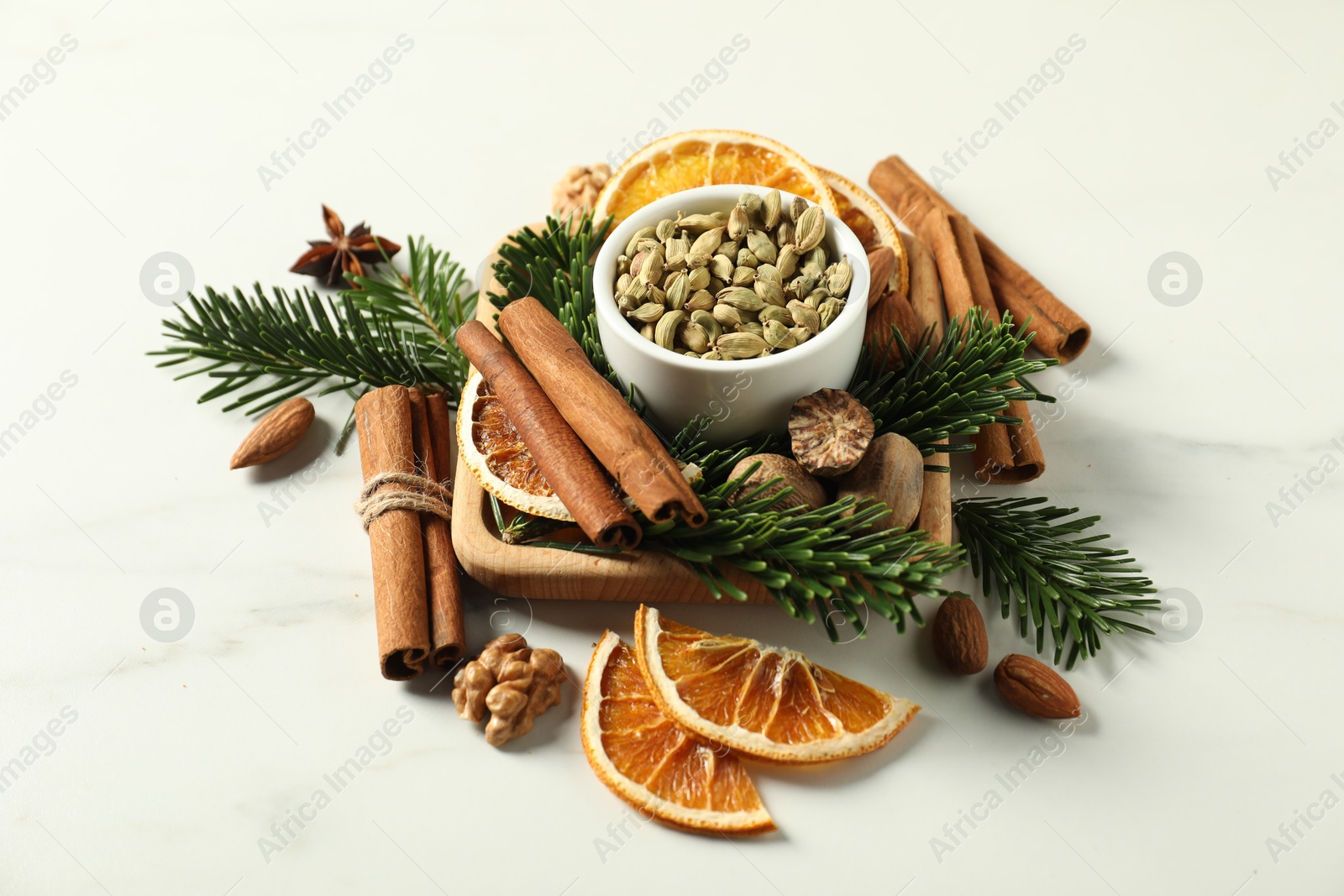 Photo of Different spices, dried orange slices and fir tree branches on white marble table. Christmas season