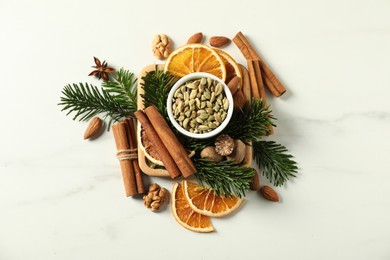 Photo of Different spices, dried orange slices and fir tree branches on white marble table, flat lay. Christmas season