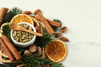 Photo of Different spices, dried orange slices and fir tree branches on white marble table, above view with space for text. Christmas season