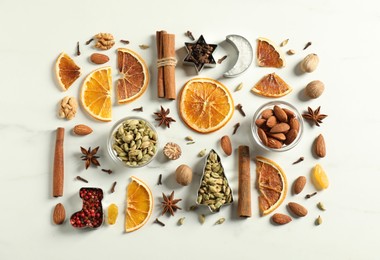 Photo of Different spices and dried orange slices on white marble table, flat lay. Christmas season