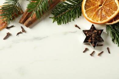 Photo of Different spices, dried orange slices and fir tree branches on white marble table, flat lay with space for text. Christmas season