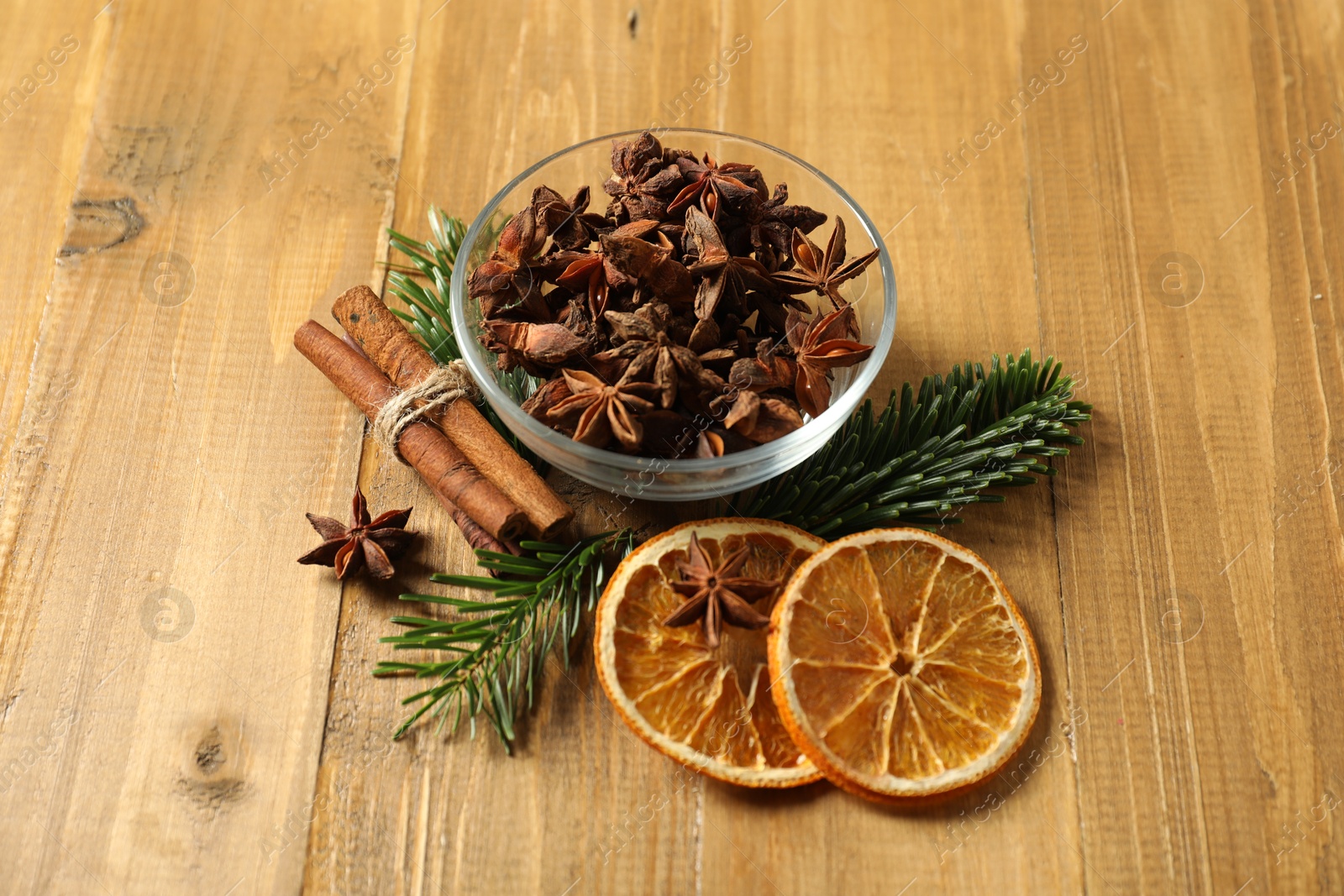 Photo of Different spices, dried orange slices and fir tree branches on wooden table. Christmas season