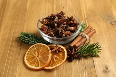 Photo of Different spices, dried orange slices and fir tree branches on wooden table. Christmas season