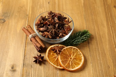 Photo of Different spices, dried orange slices and fir tree branch on wooden table. Christmas season