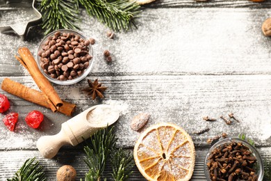 Photo of Different aromatic spices and fir tree branches on wooden table, flat lay with space for text. Christmas season